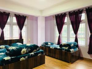 two beds in a room with purple curtains at Hotel Cozi Inn Bomdila in Bomdila