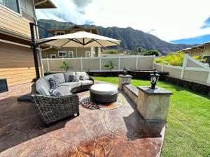 a patio with a couch and a table and an umbrella at New 4 Bedroom Home with Ocean and Gorgeous Mountain Views in the gated community of Mauna Olu in Waianae