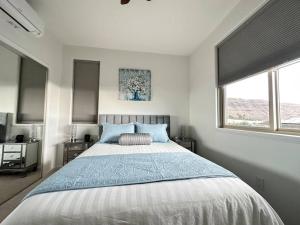 a bedroom with a large bed and two windows at New 4 Bedroom Home with Ocean and Gorgeous Mountain Views in the gated community of Mauna Olu in Waianae