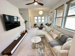 uma sala de estar com um sofá e uma televisão de ecrã plano em New 4 Bedroom Home with Ocean and Gorgeous Mountain Views in the gated community of Mauna Olu em Waianae