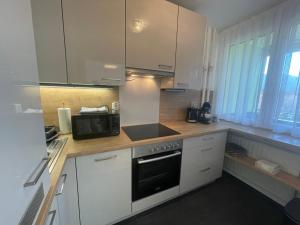 a kitchen with white cabinets and a black microwave at George-Beach Apartment Ossiachersee/Gerlitzen in Bodensdorf