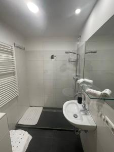 een witte badkamer met een wastafel en een douche bij George-Beach Apartment Ossiachersee/Gerlitzen in Bodensdorf