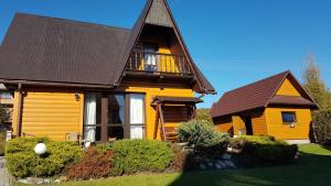 a yellow house with a brown roof at Domek w górach in Kluszkowce