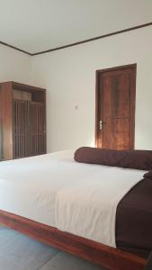 a bedroom with a large white bed with wooden doors at The luxe villas lombok in Kuta Lombok