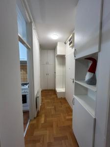 małą kuchnię z białymi szafkami i czerwonym kapeluszem na półkach w obiekcie Apartment Lenbonne w Zagrzebiu