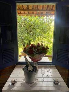 un jarrón de flores sobre una mesa con una ventana en Refugio do Amor en São João del Rei