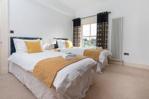 1 dormitorio con 2 camas y ventana en Thrushley Cottage in Wakefield - sleeps 7 - with roof terrace, 