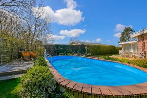 ユリアーナドルプにあるVakantiehuis Springtij met privé zwembad - Julianadorp aan Zeeの木製デッキ付きの庭のスイミングプール
