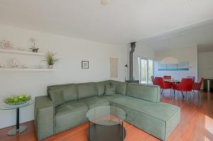 ユリアーナドルプにあるVakantiehuis Springtij met privé zwembad - Julianadorp aan Zeeの緑のソファとテーブルのあるリビングルーム