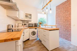 a kitchen with white cabinets and a brick wall at Stay Awesome - Urban Retreat Nähe Bergpark-Wilhelmshöhe in Kassel