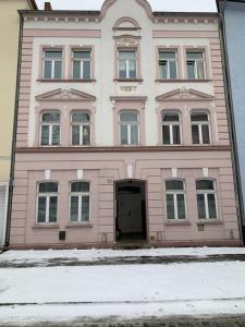 een roze gebouw met een deur ervoor bij Best-Preis FEWO Rathausblick 2 - Zentrale Lage in Wittenberge - 2 Personen - Einzelzimmer - Vollausstattung - WLAN / Prime & Self-Check-In in Wittenberge