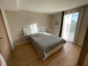 a bedroom with a bed and a large window at Ker est, Surf House, plage de Pors Carn à pieds in Penmarcʼh