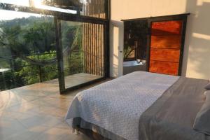 a bedroom with a bed and a large window at Duck House Hostel / La Vega in La Vega