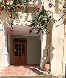 een voordeur van een huis met roze bloemen bij Athenian Asty Guesthouse in Athene