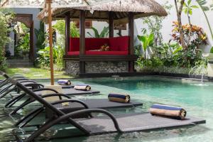 a resort pool with chairs and a gazebo at The Secret Villas in Seminyak