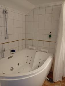 a white bath tub in a white tiled bathroom at Tällbergsgårdens Hotell in Tällberg