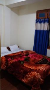 ein Schlafzimmer mit einem Bett mit einer bunten Decke darauf in der Unterkunft HOTEL DENGCHEM Bomdila in Bomdila