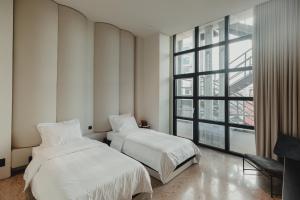 two beds in a room with a large window at Plexi Space in Athens