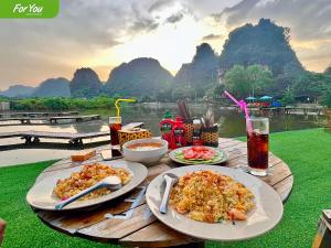 una mesa de madera con platos de comida y bebidas. en For You Homestay, en Ninh Binh