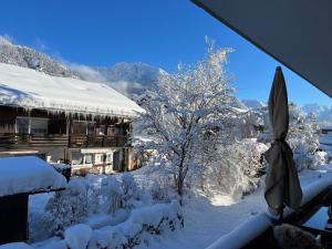 a snow covered yard with an umbrella and a house at Alpenflair Ferienwohnungen Whg 236 in Oberstdorf