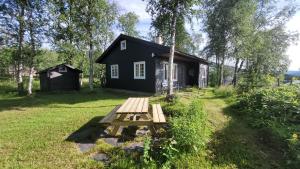 una mesa de picnic de madera frente a una casa negra en Øen Turistsenter Cottages, en Geilo