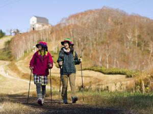 two women walking down a dirt road with poles at Naeba Prince Hotel in Yuzawa