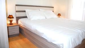 a white bed with two lamps on a night stand at Park Ej's Lake View Apartment A73 in Ohrid