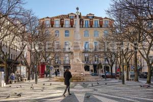 une personne marchant devant une fontaine devant un bâtiment dans l'établissement Cozy apartment in Amazing Location!, à Lisbonne
