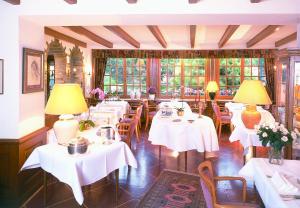 una sala da pranzo con tavoli bianchi e lampade gialle di Hotel Kinnen a Berdorf