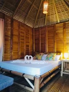 a large bed in a room with wooden walls at Mecaja Beach House in Roxas