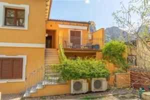 Casa amarilla con escaleras y balcón en Appartamento Mountain View, en San Pantaleo