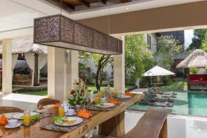 a dining room with a table with food and a pool at The Secret Villas in Seminyak
