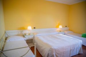 two beds in a room with yellow walls at Mendolia Beach Hotel in Taormina