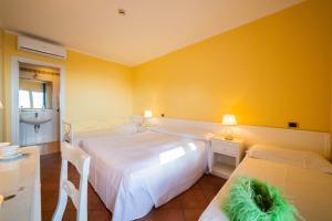 two beds in a room with yellow walls at Mendolia Beach Hotel in Taormina