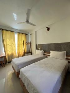 1 dormitorio con 2 camas y ventana en Leisure Boutique Maafushi 维尼家 en Maafushi