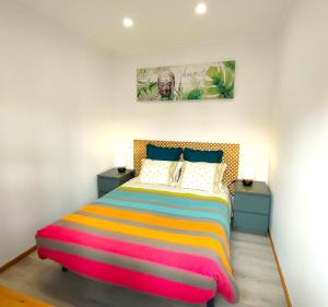 een slaapkamer met een kleurrijk bed en 2 nachtkastjes bij Herama House in Vila Nova de Gaia
