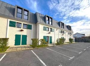 a building with green doors in a parking lot at Kyriad Argenteuil in Argenteuil