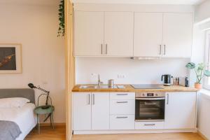 a kitchen with white cabinets and a sink next to a bed at Porto serenity studio in Porto