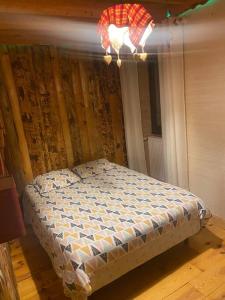 Bett in einem Zimmer mit Kronleuchter in der Unterkunft Appartement chaleureux (chalets) in Rencurel