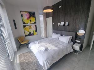 a bedroom with a large white bed and a chair at JTower Royal Suites - Alefimmoed in Jerusalem