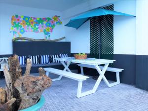 een witte picknicktafel en bank in een kamer bij The Waves Hostel in São Vicente