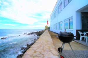 een grill aan de kant van een gebouw naast de oceaan bij The Waves Hostel in São Vicente