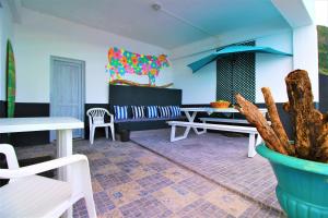 - un salon avec une table, des chaises et une plante dans l'établissement The Waves Hostel, à São Vicente