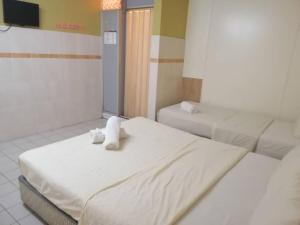 une chambre avec deux lits avec un ours en peluche dans l'établissement Grand Heritage Hotel, à Malacca