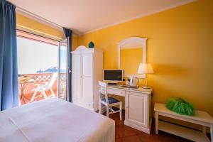 a bedroom with a bed and a desk with a computer at Mendolia Beach Hotel in Taormina