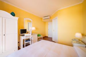 a bedroom with a bed and a desk with a computer at Mendolia Beach Hotel in Taormina