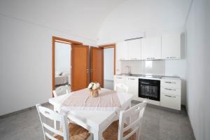 a white kitchen with a table and white cabinets at Bellariva House in Monopoli +10 photos