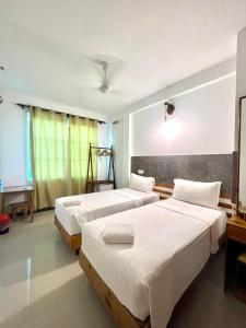 Habitación de hotel con 3 camas y mesa en Leisure Boutique Maafushi 维尼家 en Maafushi