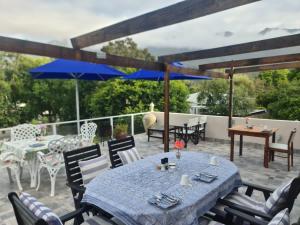 a patio with tables and chairs and blue umbrellas at The View Swellendam B&B in Swellendam