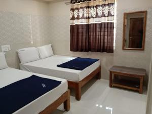 a small room with two beds and a table at Vishnu Bhavan in Tirupati
